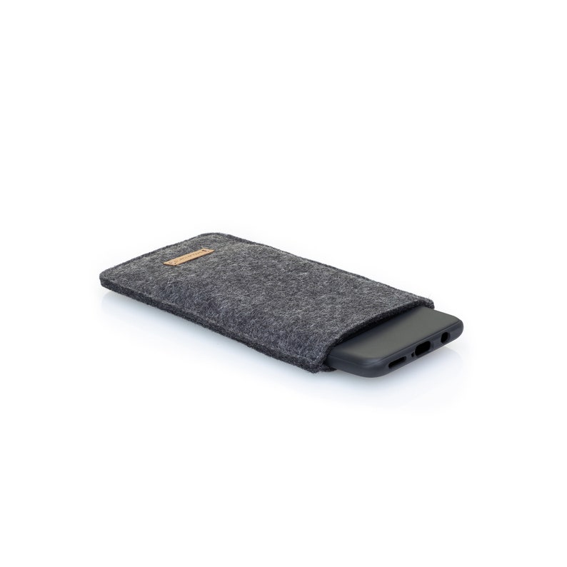 May include: A gray felt phone case with a brown leather patch. The case is designed to protect a smartphone.