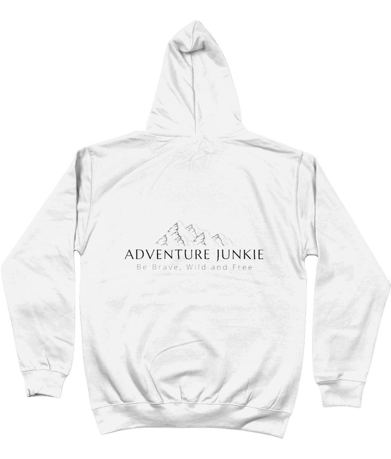 May include: White hoodie with a drawstring hood and long sleeves. The back of the hoodie features the text "ADVENTURE JUNKIE" above a mountain graphic, with the words "Be Brave, Wild and Free" below the text. The hoodie is made of a soft material.