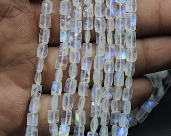 May include: A strand of white moonstone beads with a rectangular shape. The beads have a iridescent sheen.