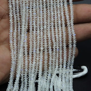 May include: A strand of white moonstone beads, faceted and strung on a thread. The beads are small and have a subtle iridescent shimmer.