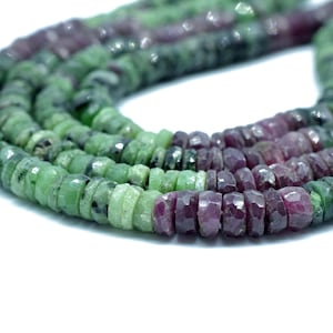 May include: A strand of green and pink gemstone beads. The beads are faceted and have a slightly irregular shape.
