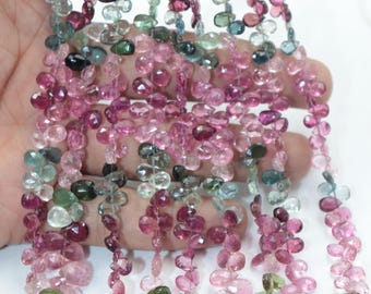 May include: A strand of multi-colored gemstone beads. The beads are oval shaped and have a variety of colors, including pink, green, and blue. The beads are strung on a clear thread.