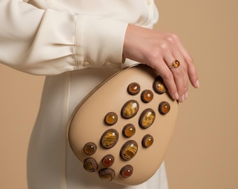 Golden Serenity: pochette a mano in pelle beige a forma di uovo con pietre di occhio di tigre e onice