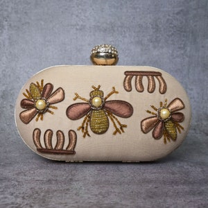 Silken Elegance: Beige Bee Clutch Adorned with Pearl Brilliance
