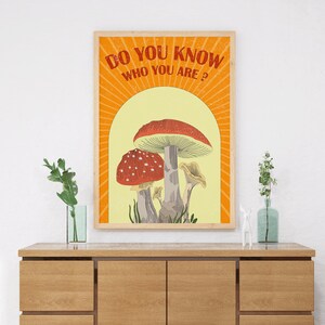 May include: A framed art print featuring a whimsical illustration of mushrooms in shades of red, white, and gray against a yellow backdrop. The text "DO YOU KNOW WHO YOU ARE?" is displayed in orange. The artwork is in a wooden frame.