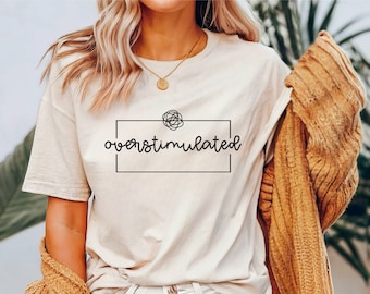 May include: A white t-shirt with a black graphic that says "overstimulated" with a doodle of a tangled line inside a box.