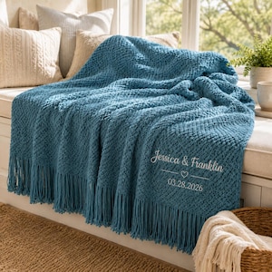 May include: A teal blue knitted throw blanket featuring a textured diamond pattern and long fringe trim. The blanket is embroidered with the white text "Jessica & Franklin" above a small heart icon and the date "03.28.2026" in a script font.