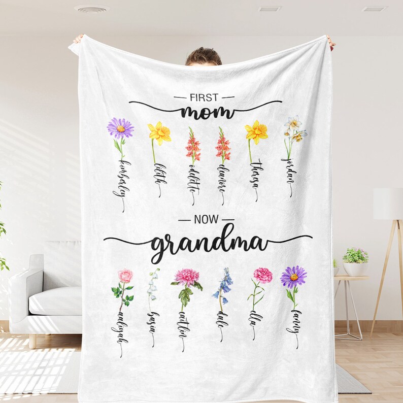 K&ouml;nnte beinhalten: Eine wei&szlig;e Fleece-Decke mit dem Text "FIRST - mom" und "NOW - grandma" darauf gedruckt. Die Decke zeigt ein Blumenmuster mit den Namen der Kinder und Enkelkinder unter jeder Blume.