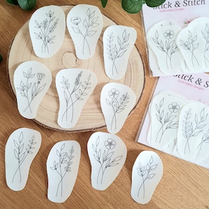 Könnte beinhalten: Ein Set mit 12 Bügelbildern mit einfachen Blumenmotiven. Die Designs sind auf weißem Stoff gedruckt und können auf Stoff gebügelt werden.