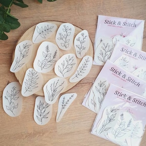 Könnte beinhalten: Ein Set mit 10 Stickmustern mit einfachen Linienzeichnungen verschiedener Blätter und Zweige. Die Muster sind auf weißem Papier gedruckt und in durchsichtigen Plastiktüten verpackt. Die Tüten sind mit "Stick & Stitch Embroidery Designs" beschriftet.