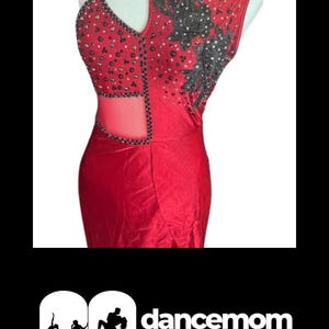 May include: Red sleeveless dance dress with intricate beadwork and a cutout design. The dress features a halter strap and a flowing skirt. The bodice is embellished with black and silver accents. The logo "dancemom.life" is at the bottom.