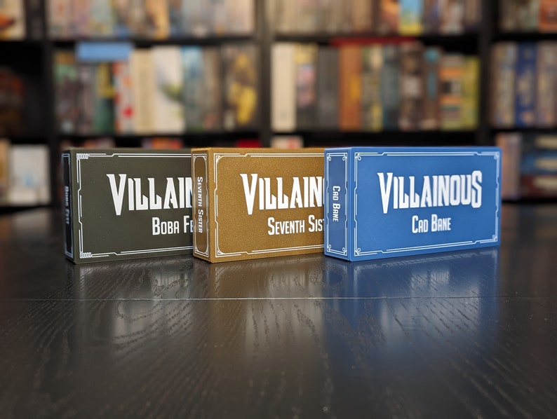May include: Three game boxes, one green, one gold, and one blue, with the text "Villain" and "Villainous" on them. The boxes are for card games.