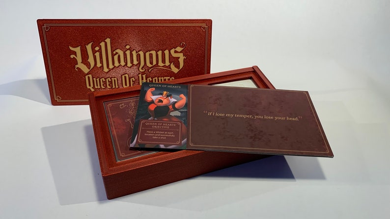 K&ouml;nnte beinhalten: Eine rote Box mit den Worten "Villainous Queen of Hearts" auf dem Deckel. Die Box ist ge&ouml;ffnet und enth&auml;lt eine Karte mit einem Bild der Herzk&ouml;nigin aus Disneys Alice im Wunderland. Die Karte lautet "Queen of Hearts -  BRUTAL TIFE" und "Zeige jedem Spieler eine Schurkenkarte. Sie m&uuml;ssen sofort einen Treffer einstecken."