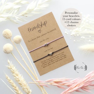 Può includere: Set di braccialetti dell'amicizia con due cordini, uno viola e uno nero, con ciondoli a forma di cuore argentati. La carta recita "L'amicizia è un nodo che non può essere sciolto. Uno per te, uno per me." Dice anche "Lega questo braccialetto intorno al tuo polso e non dimenticare di esprimere un desiderio. Si dice che quando si consuma, il tuo desiderio si avvererà." La carta dice anche "Personalizza i tuoi braccialetti. 15 colori di cordino + 12 opzioni di ciondoli." ed è firmata "G.G."