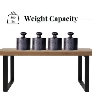 May include: A wooden table with black metal legs supports four black cylindrical weights. The image includes text indicating a weight capacity of 300 lbs.