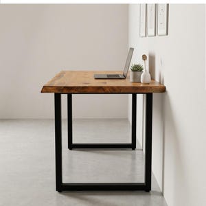 May include: A wooden desk with a natural edge and black metal legs. A laptop, a small potted succulent, and a white vase are on the desk. The desk is approximately 60 inches long.