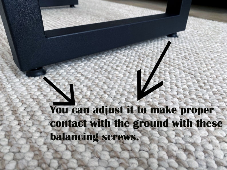 May include: Close-up of a black metal furniture leg with adjustable feet. The image shows how to adjust the feet to make proper contact with the ground using balancing screws. The leg is on a textured, neutral-colored rug.