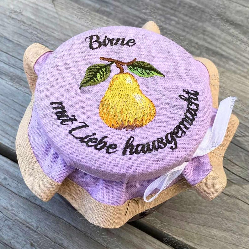 May include: A purple fabric jar lid with a brown burlap trim. The lid has an embroidered pear with green leaves and the text "Birne mit Liebe hausgemacht".