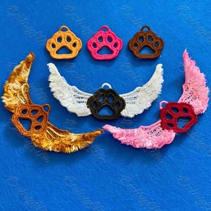 May include: A collection of embroidered patches featuring paw prints and wings. The patches are in various colors, including orange, pink, brown, white, and pink. The paw prints have a loop at the top for attachment.