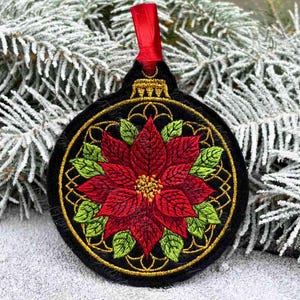 May include: Black Christmas ornament with a red poinsettia design, green leaves, and gold accents. The ornament has a red ribbon for hanging. The poinsettia is the focal point, surrounded by a gold filigree pattern.