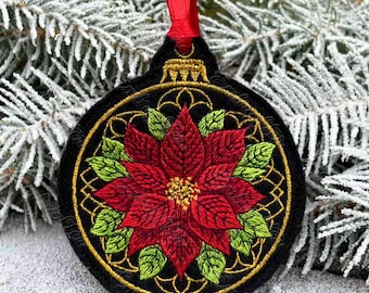 May include: Black Christmas ornament with a red poinsettia design, green leaves, and gold accents. The ornament has a red ribbon for hanging. The poinsettia is the focal point, surrounded by a gold filigree pattern.
