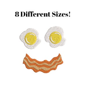 Può includere: Faccia sorridente composta da due uova bianche con tuorli gialli e una striscia di pancetta arancione. Il testo "8 Different Sizes!" è sopra l'immagine.