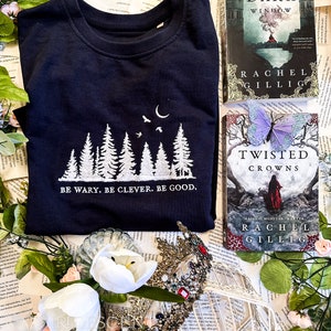 Seja cauteloso, seja inteligente, seja bom moletom bordado com gola redonda, oficialmente licenciado One Dark Window The Shepherd King por Rachel Gillig Merch