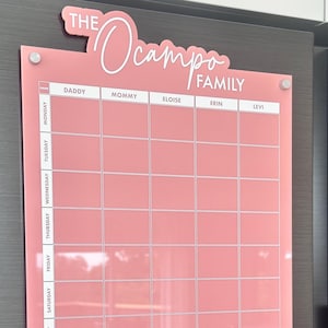 May include: Pink family meal planner with the text "The Ocampo Family" at the top. The planner has sections for each day of the week and family members. It also includes sections for meal planning and reminders.