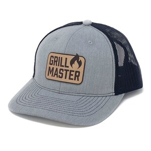 May include: A gray and black trucker hat with a brown leather patch that says "Grill Master" with a flame icon.
