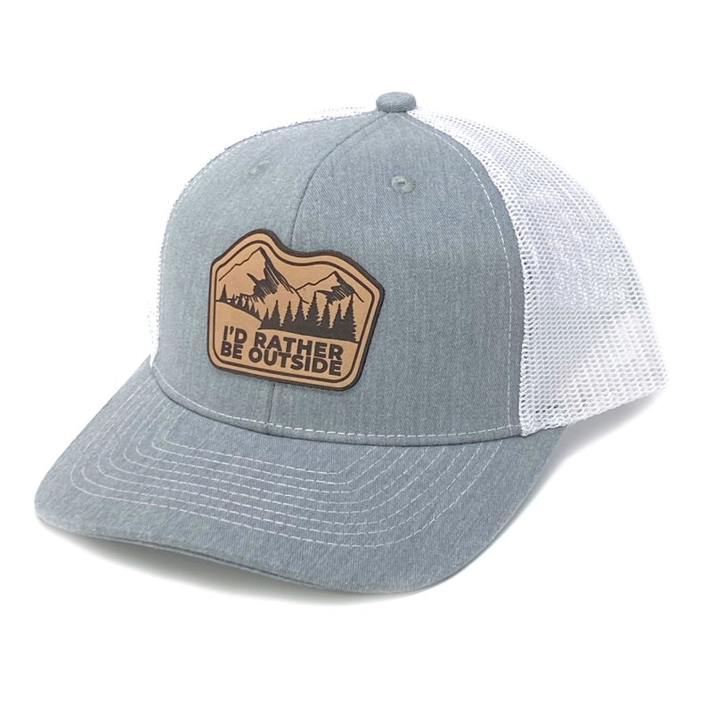 Puede incluir: Una gorra de camionero gris y blanca con un parche de cuero marr&oacute;n que dice "I'd Rather Be Outside" y presenta una escena de monta&ntilde;a.