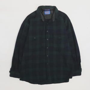 May include: A long-sleeve button-down shirt in a dark green and black plaid pattern. The shirt features a pointed collar, a front button placket, and two chest pockets with buttoned flaps. A blue Pendleton brand label is visible inside the collar.