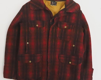 Könnte beinhalten: Rot-schwarz karierte Jacke mit breitem Kragen und vier Vordertaschen. Die Jacke hat goldfarbene Knöpfe und ein beiges Futter, das am Kragen sichtbar ist. Die Jacke ist aus einem dicken, warmen Material.