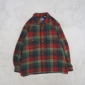 Könnte beinhalten: Ein langärmeliges Hemd mit Knopfleiste und einem Karomuster in den Farben Rot, Dunkelgrün und Marineblau. Das Hemd verfügt über einen klassischen Kragen, zwei Brusttaschen mit geknöpften Klappen und eine durchgehende Knopfleiste vorne.