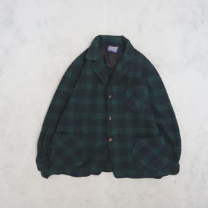 May include: A long-sleeve button-up jacket featuring a dark green and black plaid pattern. The jacket includes a notched collar, a single chest pocket on the left side, two large patch pockets at the waist, and a black interior lining with a label.