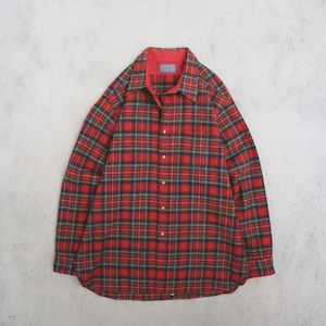 Può includere: Una camicia a maniche lunghe abbottonata con un motivo a quadri rosso, nero e verde. La camicia presenta un colletto a punta, un'abbottonatura frontale con bottoni chiari e un'etichetta blu del marchio Pendleton cucita sul colletto.