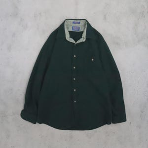 May include: A dark forest green long-sleeve button-down shirt featuring a light sage green inner collar lining and a single chest pocket. The shirt has a classic collar, a front button placket, and a Pendleton brand label inside the neck.