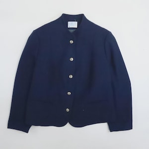 May include: A dark navy blue jacket featuring a high collar and a front button closure with five silver-toned metallic buttons. The jacket has long sleeves and a straight hemline, with a small white rectangular label visible at the inner neckline.