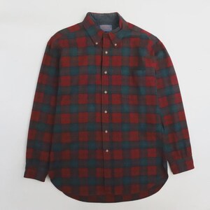 Pode incluir: Uma camisa de botão de manga comprida com um padrão xadrez clássico. A camisa apresenta um esquema de cores vermelho, verde-azulado e castanho, com uma gola abotoada e um único bolso no peito. O tecido parece ser uma flanela macia.