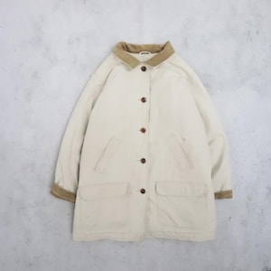 Op de afbeelding: Een crèmekleurig jack met een beige corduroy kraag en bijpassende corduroy manchetten. Het jack heeft een knoopsluiting aan de voorzijde met vijf bruine knopen, twee grote rechthoekige opgestikte zakken onderaan en twee verticale steekzakken.