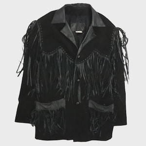 Pode incluir: Um casaco preto com longos detalhes de franjas de couro no peito, ombros e mangas. A peça inclui uma gola de couro liso, abas de bolso de couro a condizer e um fecho frontal com botões. O design incorpora costuras decorativas ao longo do jugo e dos bolsos.