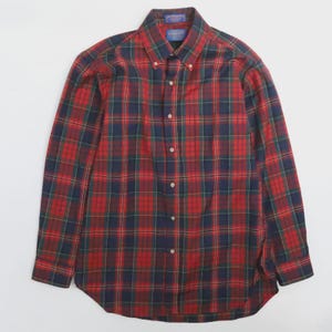 Pode incluir: Uma camisa abotoada de manga comprida com um padrão xadrez clássico. A camisa apresenta um esquema de cores vermelho, azul marinho e verde. A gola é abotoada e a camisa tem uma bainha curva. A camisa é feita de um tecido macio e tecido.