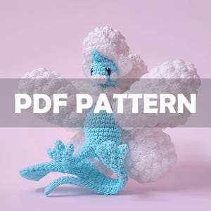 Op de afbeelding: Een gehaakt pluche speelgoed in de vorm van een wezen met een blauw lichaam en hoofd, en witte, donzige wolkenachtige kenmerken. De tekst "PDF PATTERN" staat over de afbeelding.