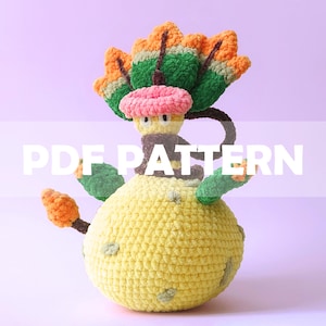 May include: A handmade crochet figure in the shape of a cartoon character. The figure has a yellow body, green and orange headpiece, and a pink hat. The text "PDF PATTERN" is overlaid on the image.