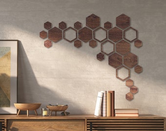 Puede incluir: Una decoración de pared de madera con un patrón de panal de abeja de color marrón claro. La decoración se muestra en una pared gris claro sobre una consola de madera con un jarrón de hierba de la pampa seca, un cuenco y libros.