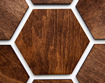 May include: A close-up of a hexagonal wooden wall panel with a dark brown stain. The panel is made up of six individual hexagons, each with a slightly different grain pattern. The hexagons are arranged in a honeycomb pattern, with the center hexagon being the largest.