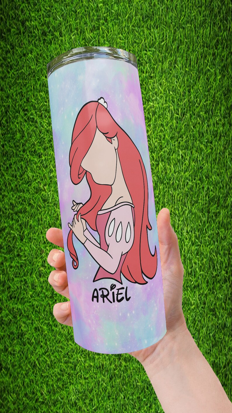 May include: A pink and blue galaxy-themed tumbler with a cartoon image of Ariel from The Little Mermaid. The tumbler has the word "Ariel" written on it.