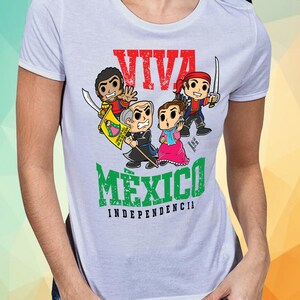 May include: White t-shirt with a green, white, and red graphic design. The graphic features cartoon characters and the text "Viva Mexico Independencia".