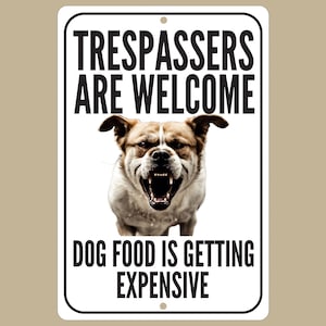 May include: White metal sign with black text that reads "Trespassers are welcome. Dog food is getting expensive."  A snarling brown and white dog is pictured in the center of the sign.