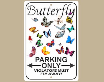 May include: White rectangular metal sign with a black border, featuring the word "Butterfly" in cursive at the top. The sign is decorated with various colorful butterfly illustrations. Below, it reads "PARKING ONLY - VIOLATORS MUST FLY AWAY!"