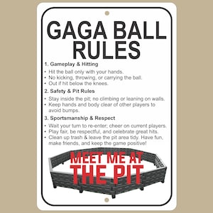 May include: A white rectangular sign with black text that reads "GAGA BALL RULES." The sign lists rules for gameplay, safety, and sportsmanship. A gray pit is at the bottom with the words "MEET ME AT THE PIT" in red.